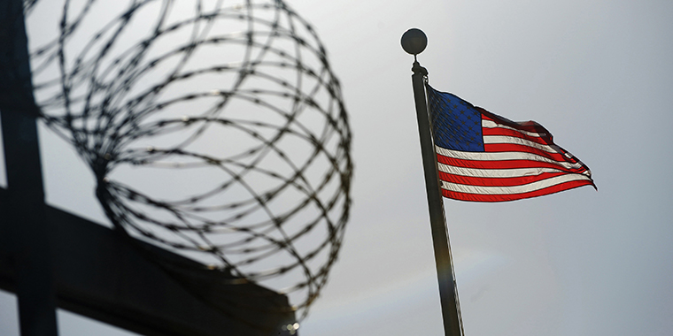 A U.S. flag flies above a razor wire-topped fence at the "Camp Six" detention facility at the U.S. Naval Station at Guantanamo Bay on December 10, 2008.
