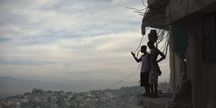 Two men stand on the edge of their partially destroyed apartment in Port-au-Prince, Haiti, on January 9, 2011, almost one year after the earthquake that killed around 250,000 people and wrecked much of the capital.