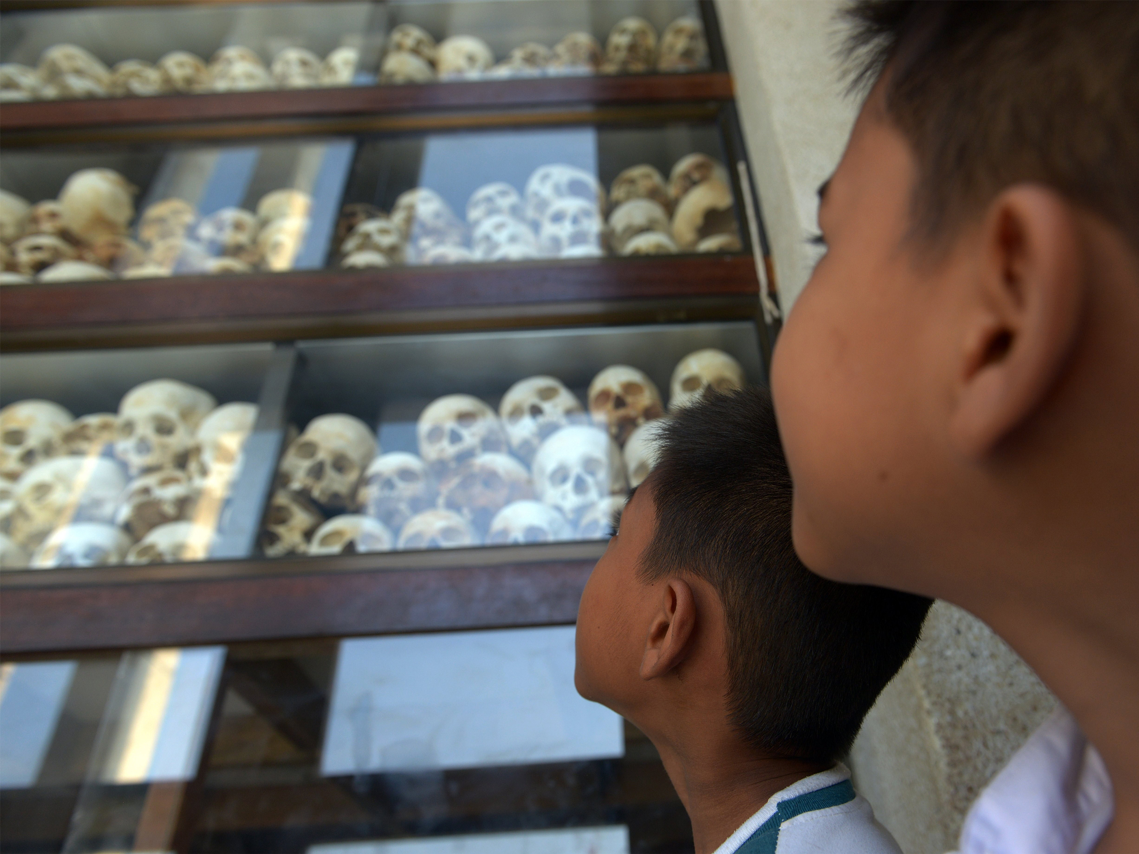 A photo showing children looking at skulls on display at the Killing Fields Memorial in Phnom Penh, Cambodia on April 17, 2014.