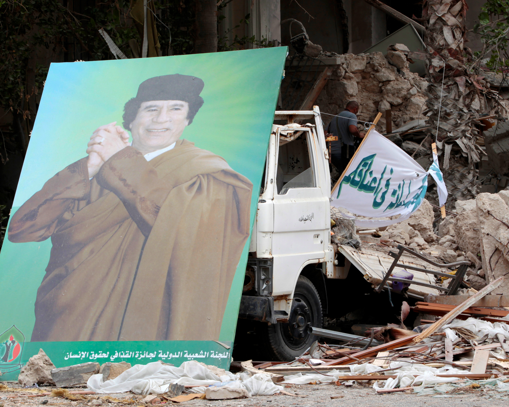 A photo of a poster of Libyan leader Muammar Gaddafi sitting in front of a building damaged by, according to the government, coalition air strikes, in Tripoli, Libya, on June 6, 2011.