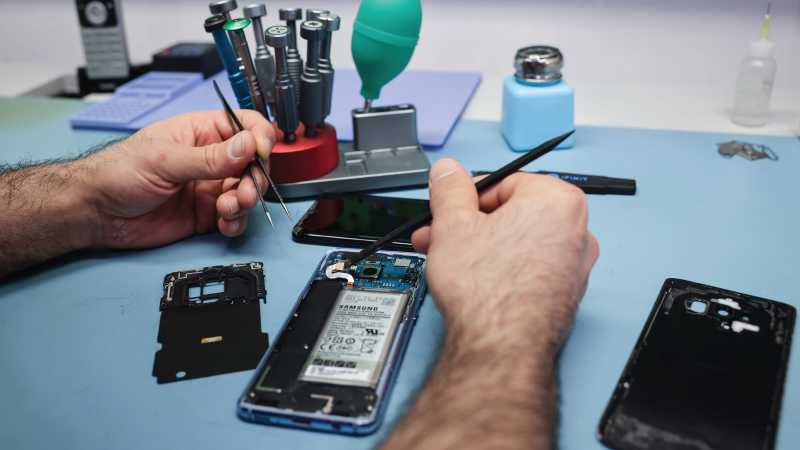 A technician works on a smartphone with a defective display in his small specialist store for repairs and accessories in Hamburg, Germany on April 23, 2024. 