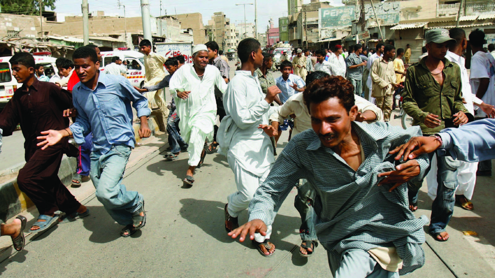 People flee from gunfire during a firefight between rival gangs in Karachi, Pakistan