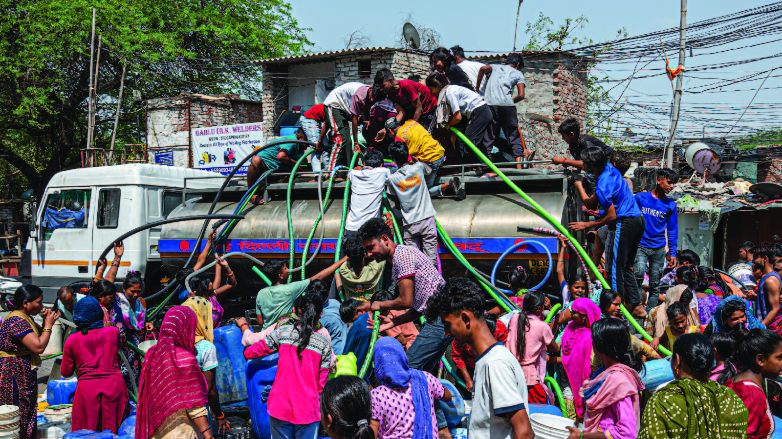 People climb atop a water tanker with pipes to fill their containers as a heat wave drives up demand and causes shortages, with the government delivering water by truck in New Delhi, India, on June 15, 2024. 