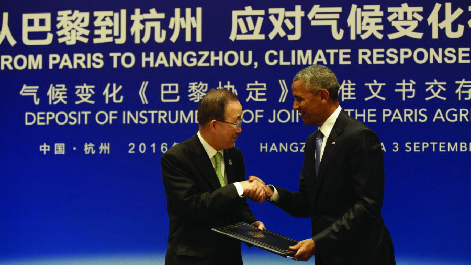 President Barack Obama hands the Paris Agreement documents to United Nations Secretary-General Ban Ki-moon during a climate event 