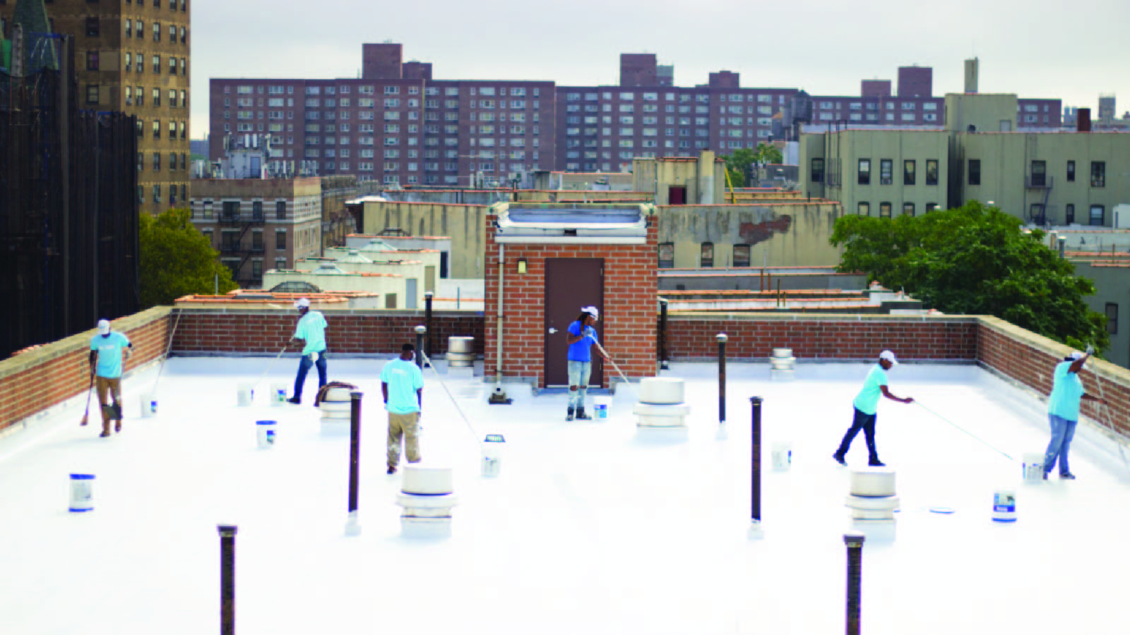 NYC CoolRoofs trainees coat a rooftop with white reflective paint. 