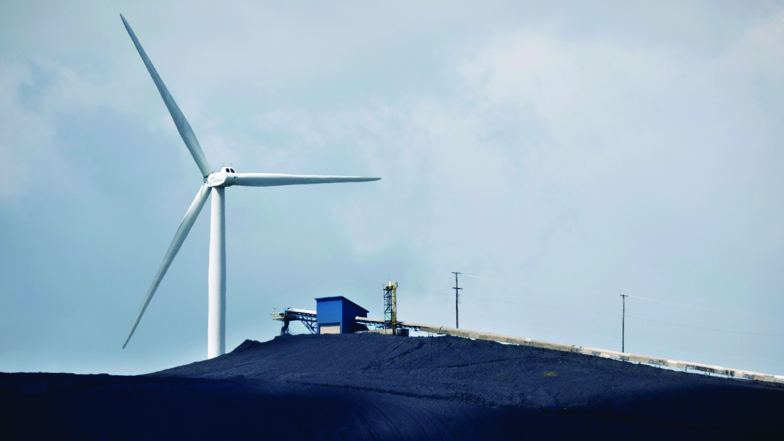 A turbine from a wind farm spins behind the Mettiki Coal processing plant in Oakland, Maryland