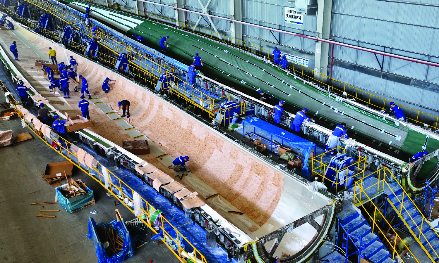 Workers manufacture huge wind turbine blades at a production facility in China