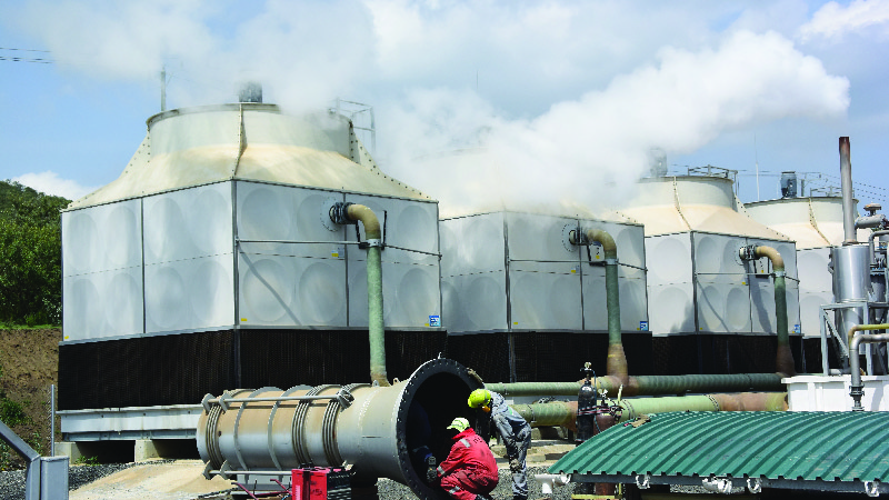 Engineers crouch in front of the Olkaria geothermal plant, which supplies clean, renewable energy, was partly funded by international development banks in Nairobi, Kenya.