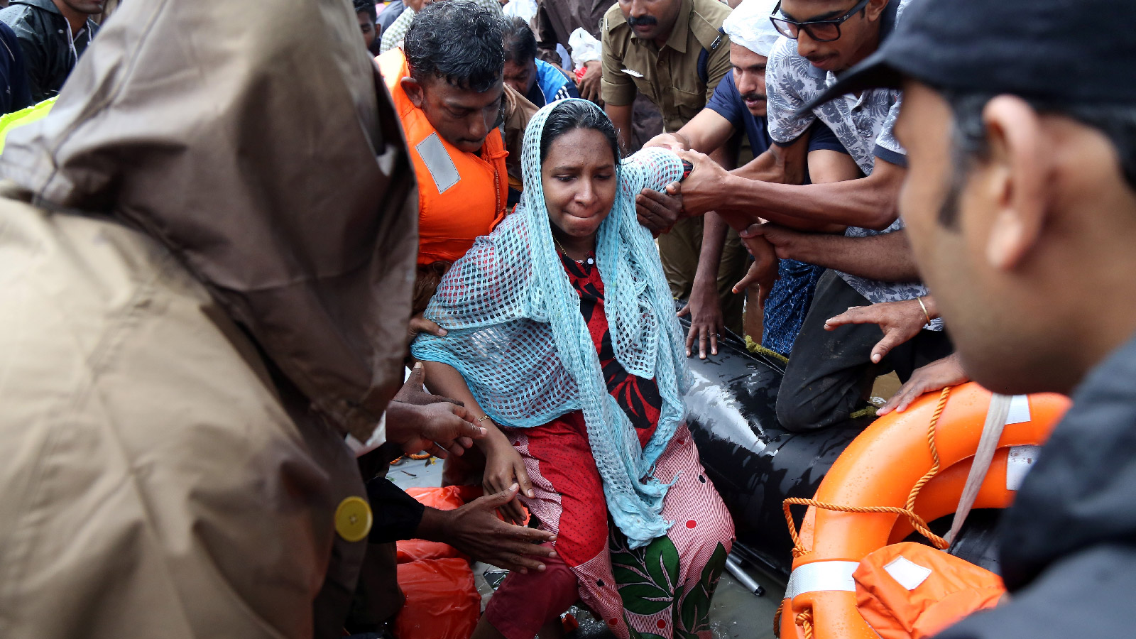 People assist a pregnant woman in disembarking a boat after she evacuated a flooded area in Aluva, India on August 18, 2018.  