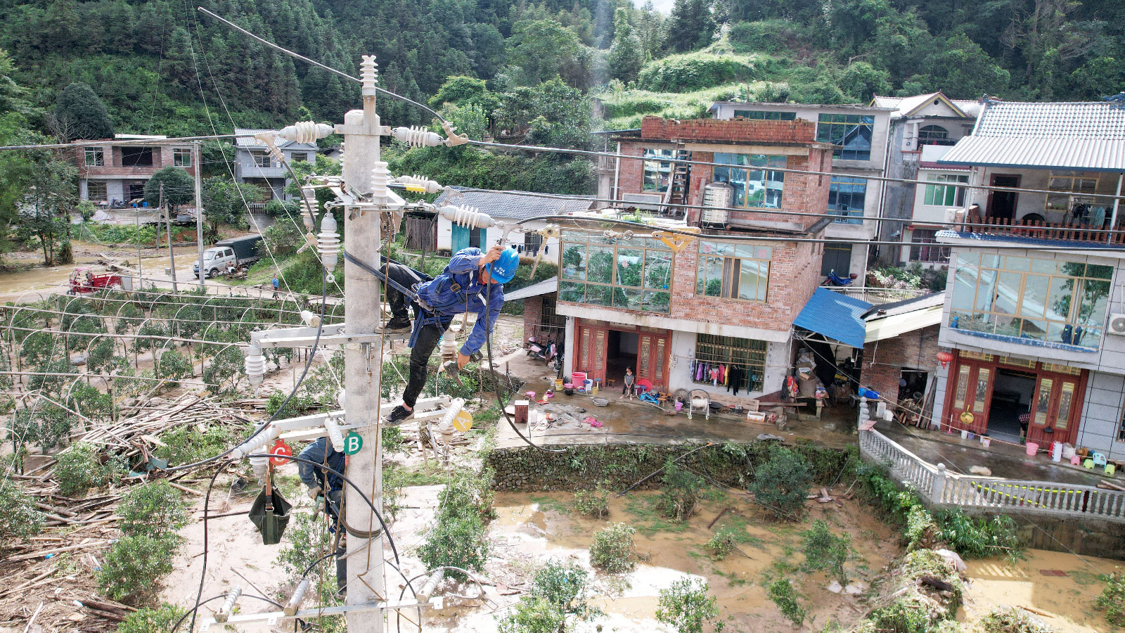 Electric power workers repair a power supply line on a pole in Rongan, China, on July 2, 2024.