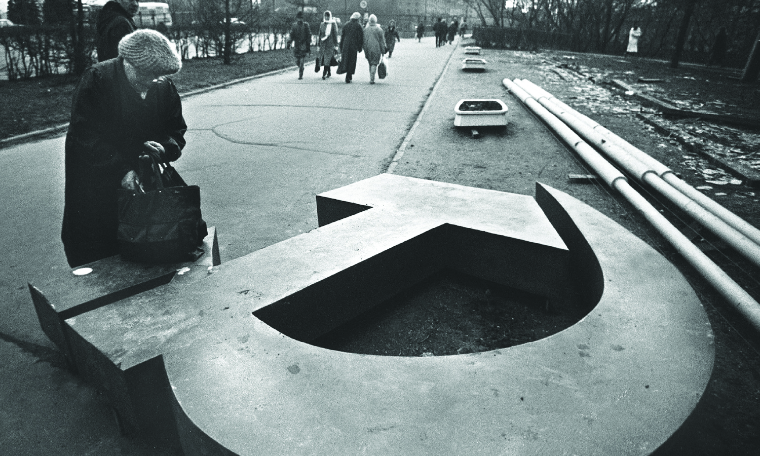 A woman reaches into her bag, which rests on a fallen Soviet hammer-and-sickle on a Moscow street in November, 1991.