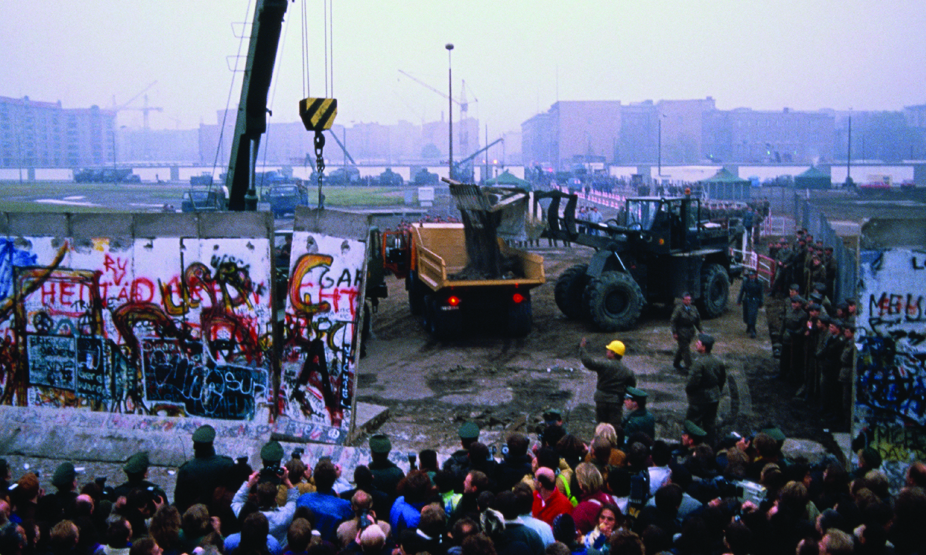 Crowd watches as workmen deconstruct the Berlin Wall in Germany in late 1989.