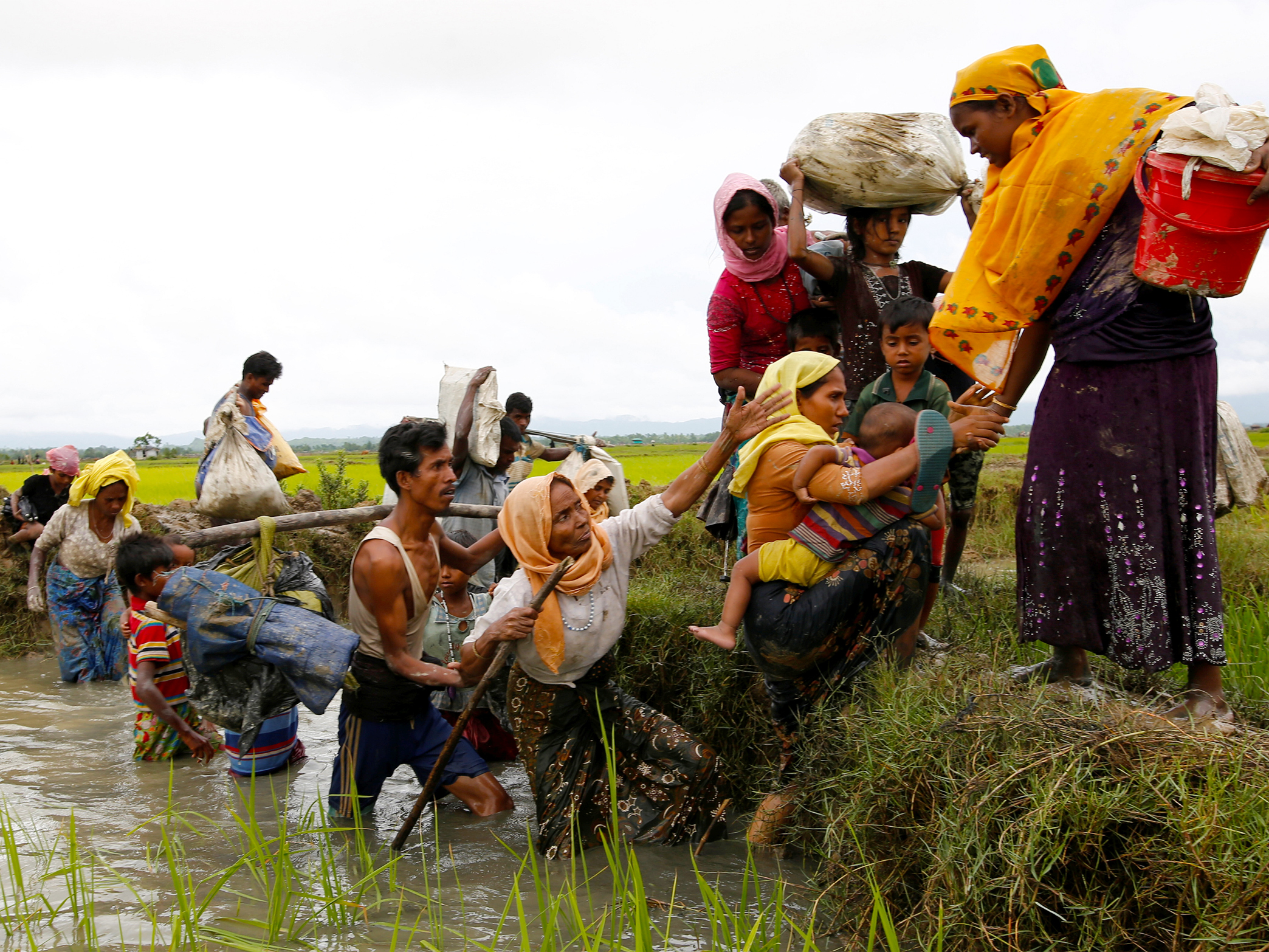 A picture of Rohingya refugees crossing a canal with various personal items after travelling over the Bangladesh-Myanmar border in Teknaf, Bangladesh.