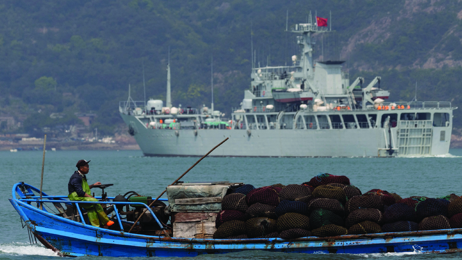 A fishing boat sails past a Chinese warship during a military drill near the Taiwan-controlled Matsu Islands on April 11, 2023. 