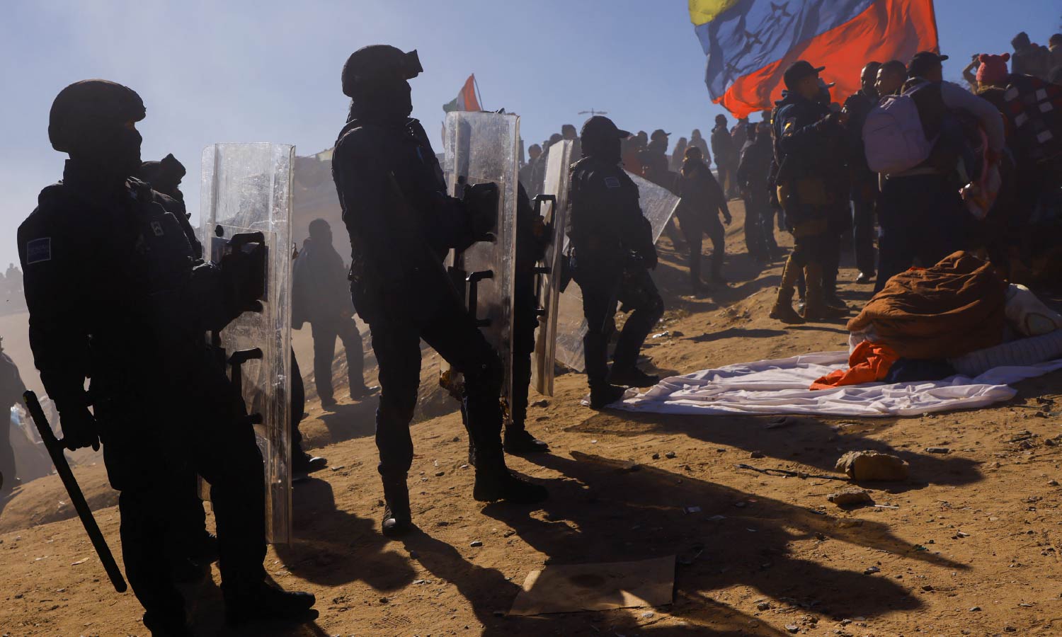Police holding protective shields remove Venezuelan migrants from a camp on the banks of the Rio Bravo river.