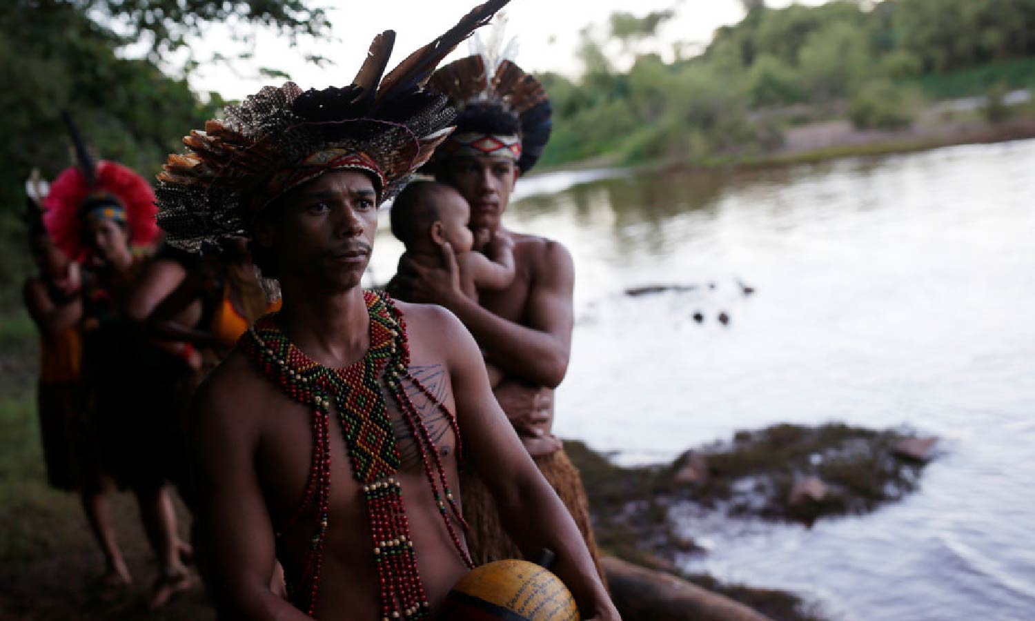 Members of the Brazilian Pataxo Ha-ha-hae tribe stand by a river.