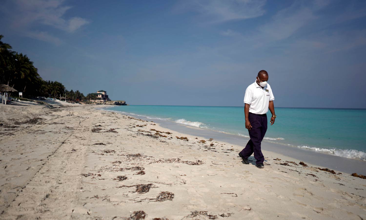 A security agent wearing a protective mask walks on the beach amid concerns about the spread of the coronavirus disease (COVID-19), in Varadero, Cuba.
