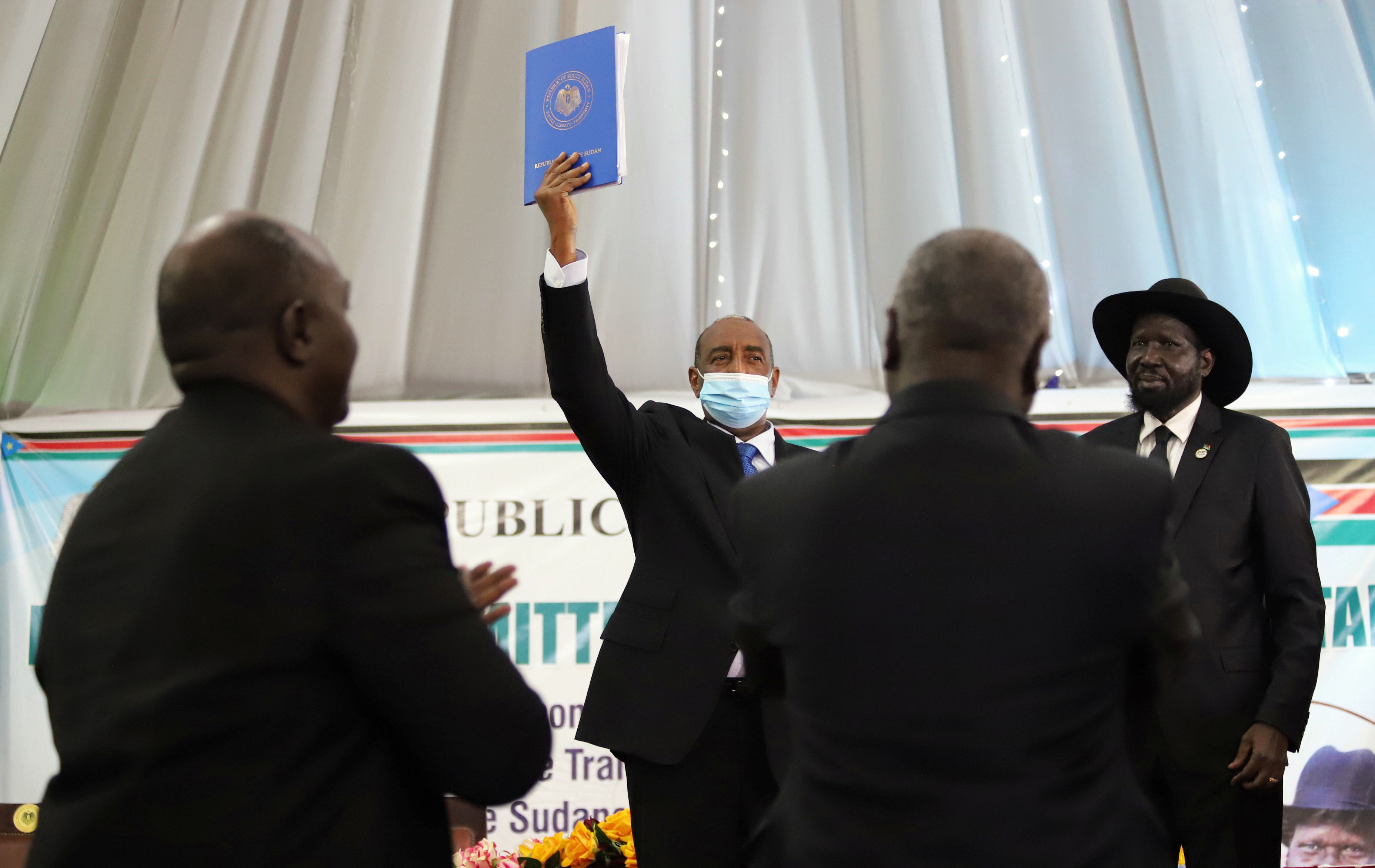 Sudan's Sovereign Council Chief General Abdel Fattah al-Burhan (center), next to South Sudan's President Salva Kiir Mayardit (far right), lifts a copy of a signed peace agreement with the country's five key rebel groups, in Juba, South Sudan August 31, 20