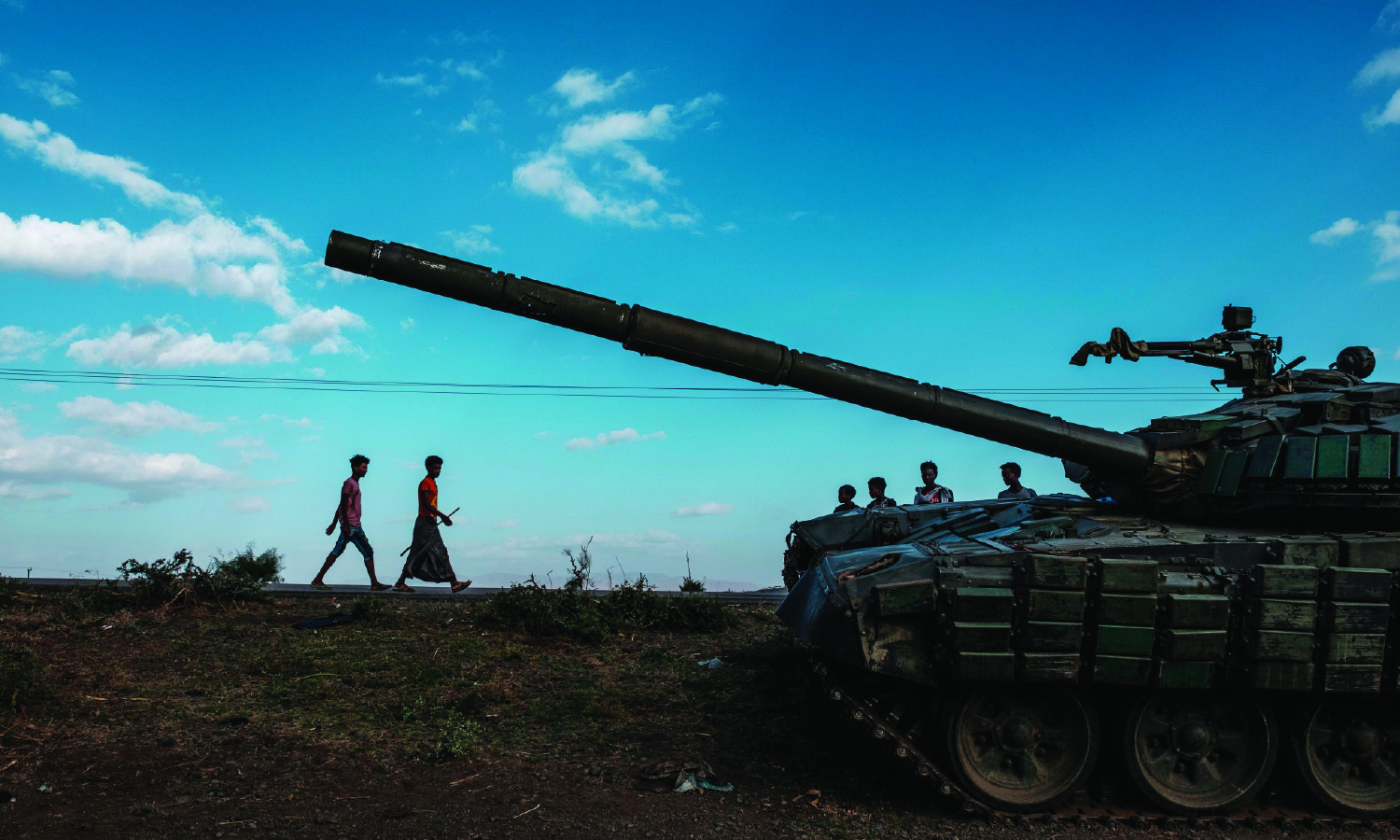 Youngsters walk next to an abandoned tank belonging to Tigrayan forces south of the town of Mehoni, Ethiopia, on December 11, 2020. 