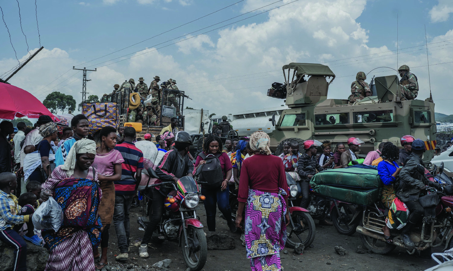 People gather near Southern African Development Community Mission vehicles while fleeing rebel-government clashes in Sake, Democratic Republic of the Congo.