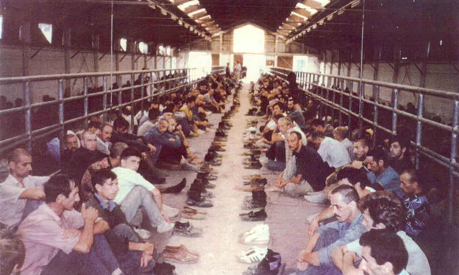 Detainees sit in rows with their shoes off and placed in front of them in the Manjaca Camp, near Banja Luka, Bosnia and Herzegovina.