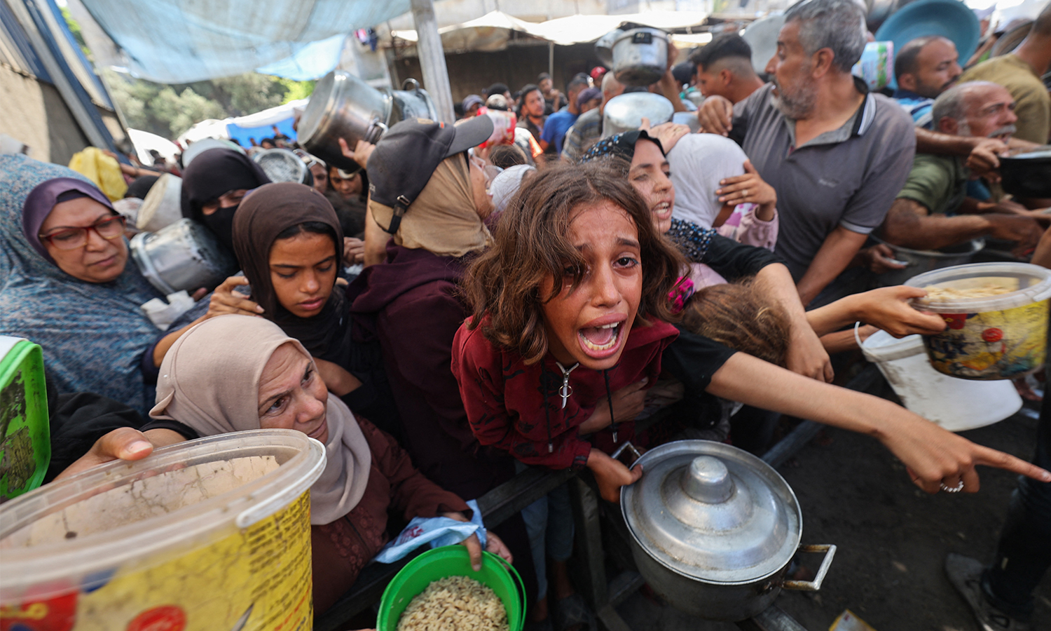 Palestinians shove to receive a hot meal from a charity kitchen.