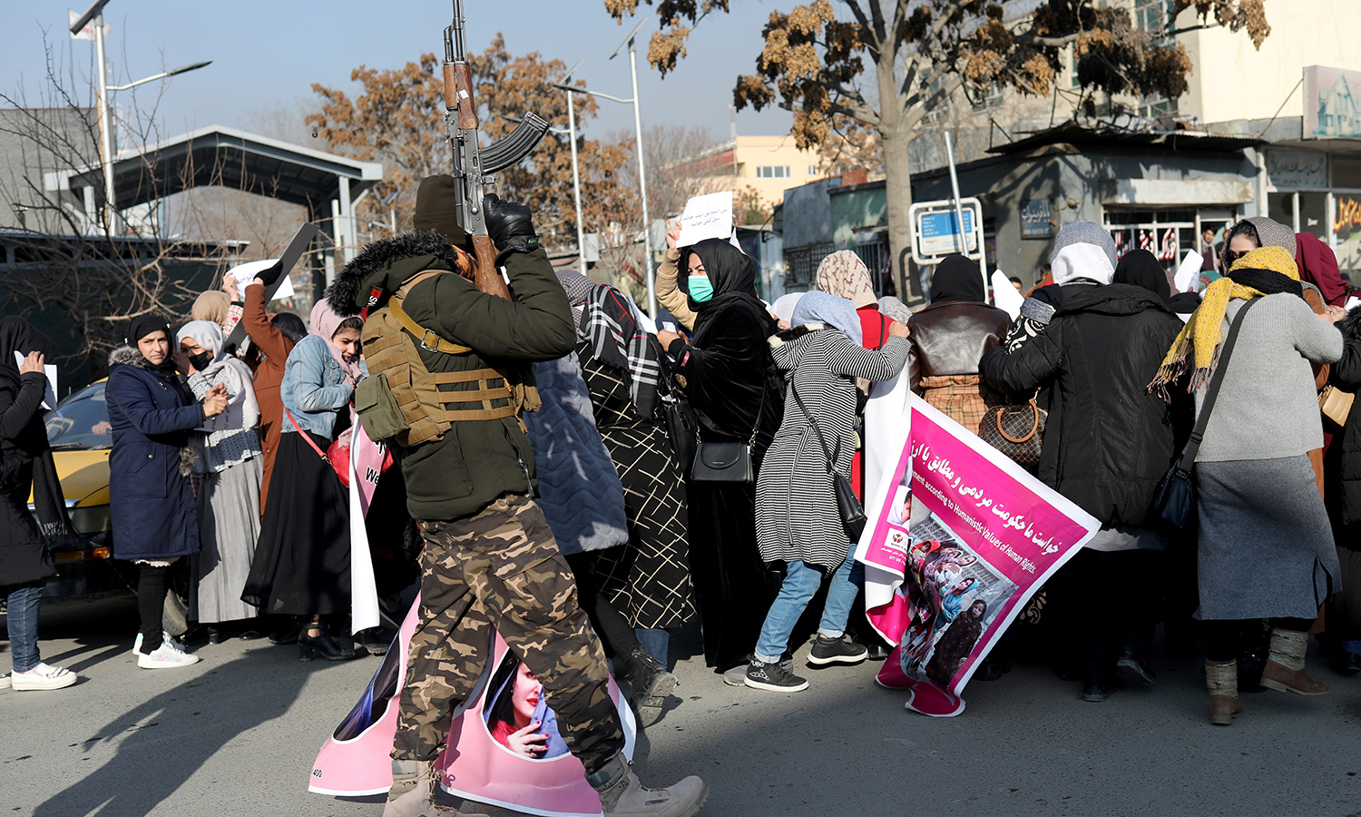 A member of Taliban forces fires in the air to disperse the Afghan women during a rally.