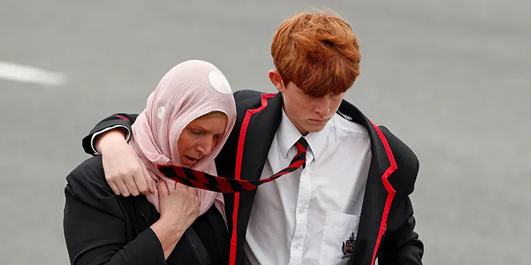 A student and a woman attend the burial ceremony of a victim of the mosque attacks, at the Memorial Park Cemetery in Christchurch, New Zealand, on March 21, 2019.