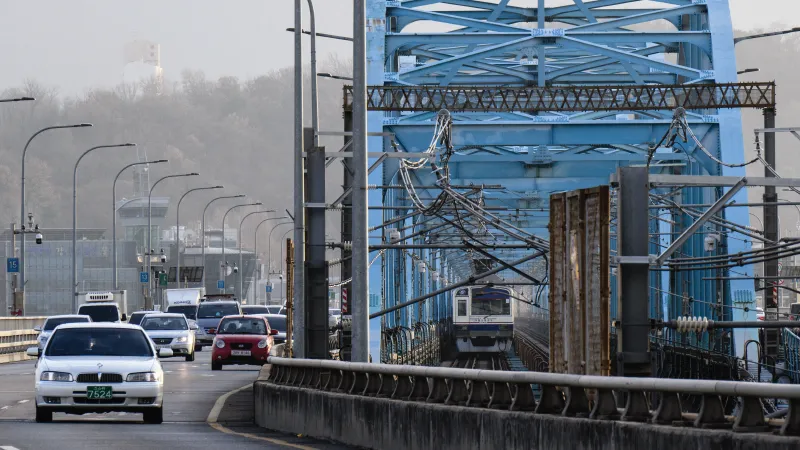 A Seoul Subway Line 4 metro train drives next to cars over the Dongjak Bridge, which runs across the Han River, in Seoul 