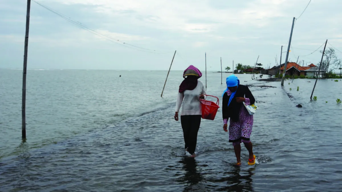 Villagers walk along a street flooded with sea water in Subang, Indonesia