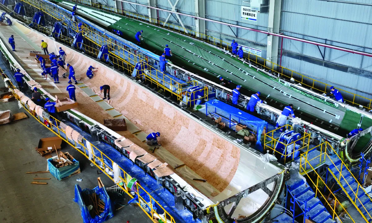 Workers manufacture huge wind turbine blades at a production facility in China