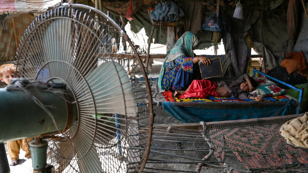 A woman uses a paper sheet to fan her child during a power cut amid a heatwave in Jacobabad, Pakistan, on May 11, 2022.