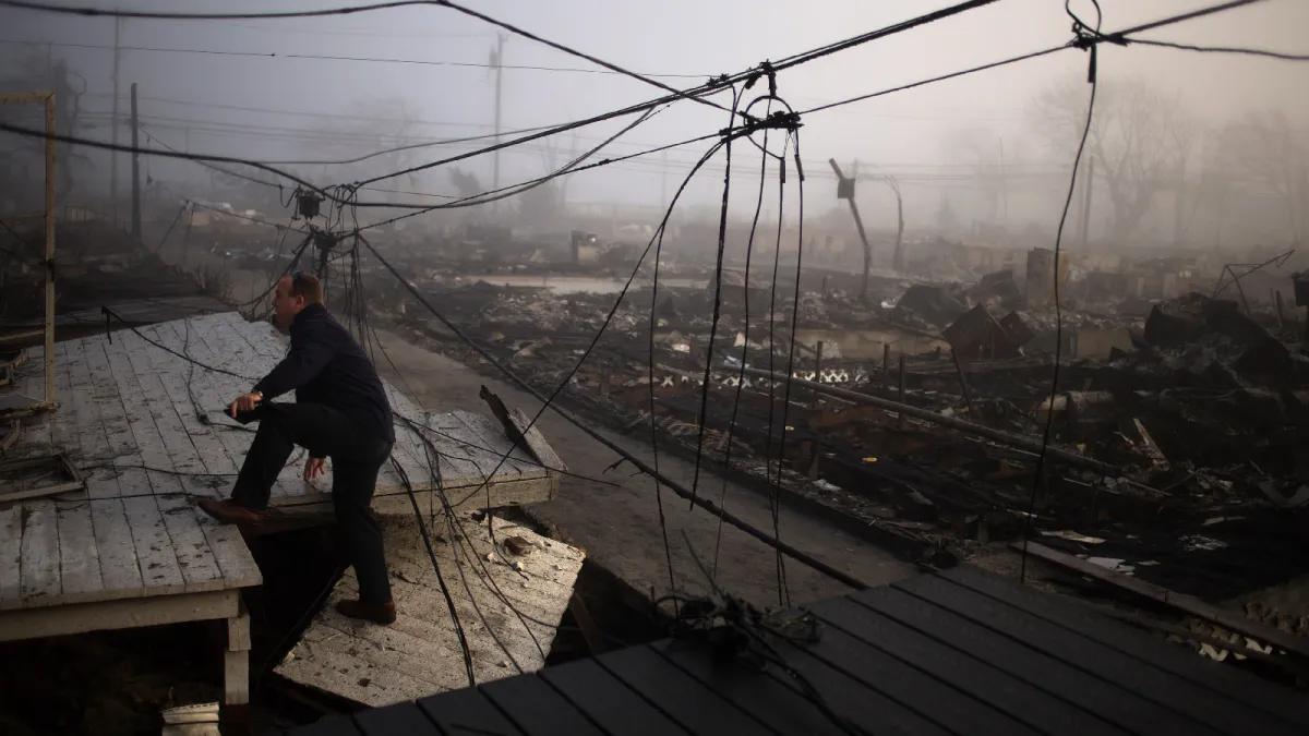 An insurance claims adjuster climbs into the entrance of a house devastated by Hurricane Sandy in Queens, New York, on November 12, 2012.