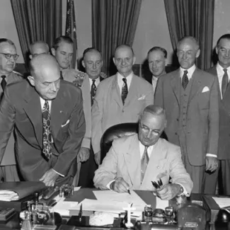 President Harry S. Truman is signing the National Security Act Amendment of 1949 in the Oval Office.