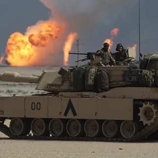 American soldiers stand in the turret of a tank in Kuwait as oil wells burn near the Iraqi border on March 20, 1991.