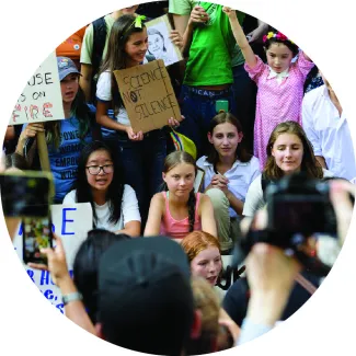 Greta Thunberg sits in the center of young climate activists in a FridaysForFuture protest in front of the UN Headquarters.