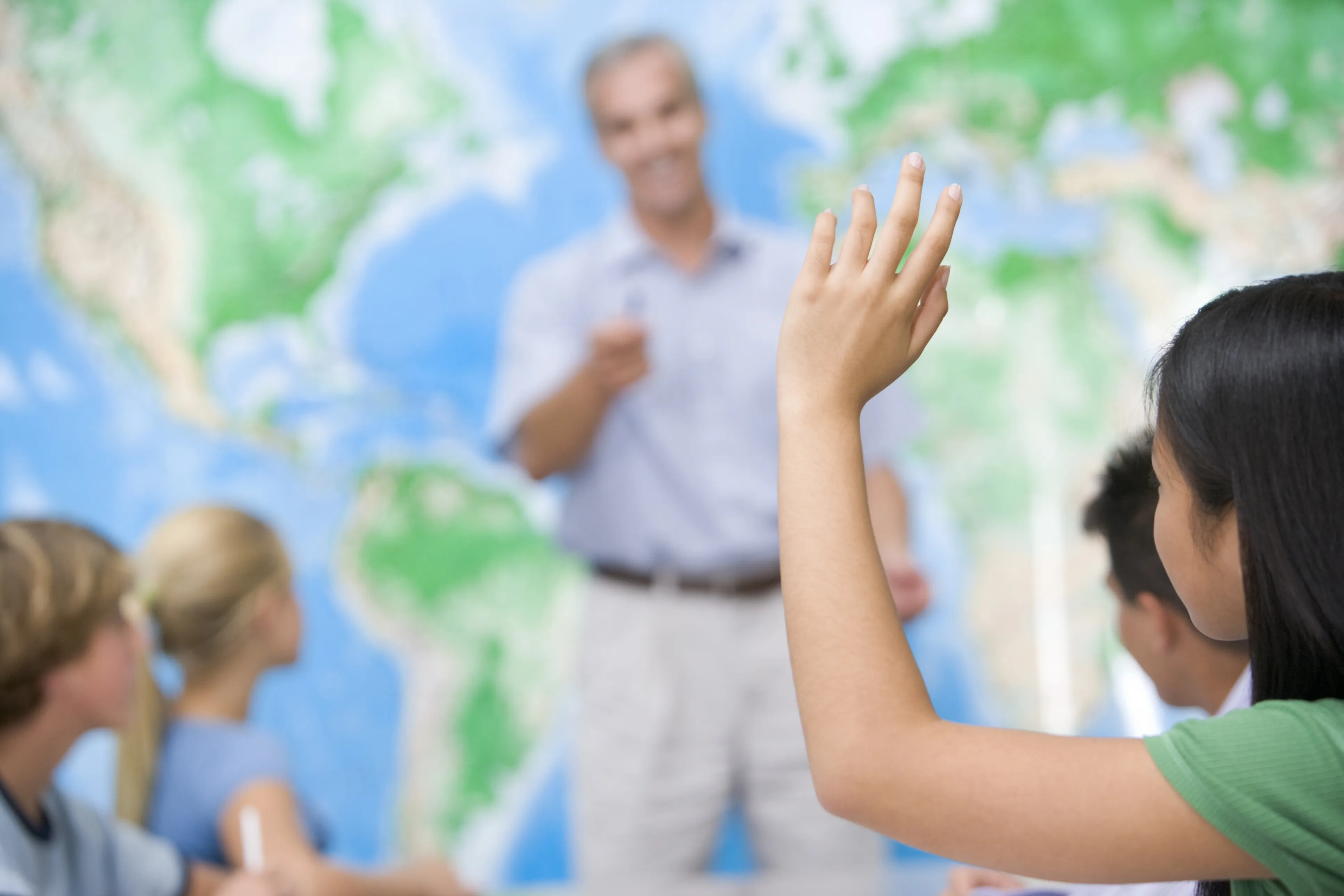 teacher calling on students with a map behind them