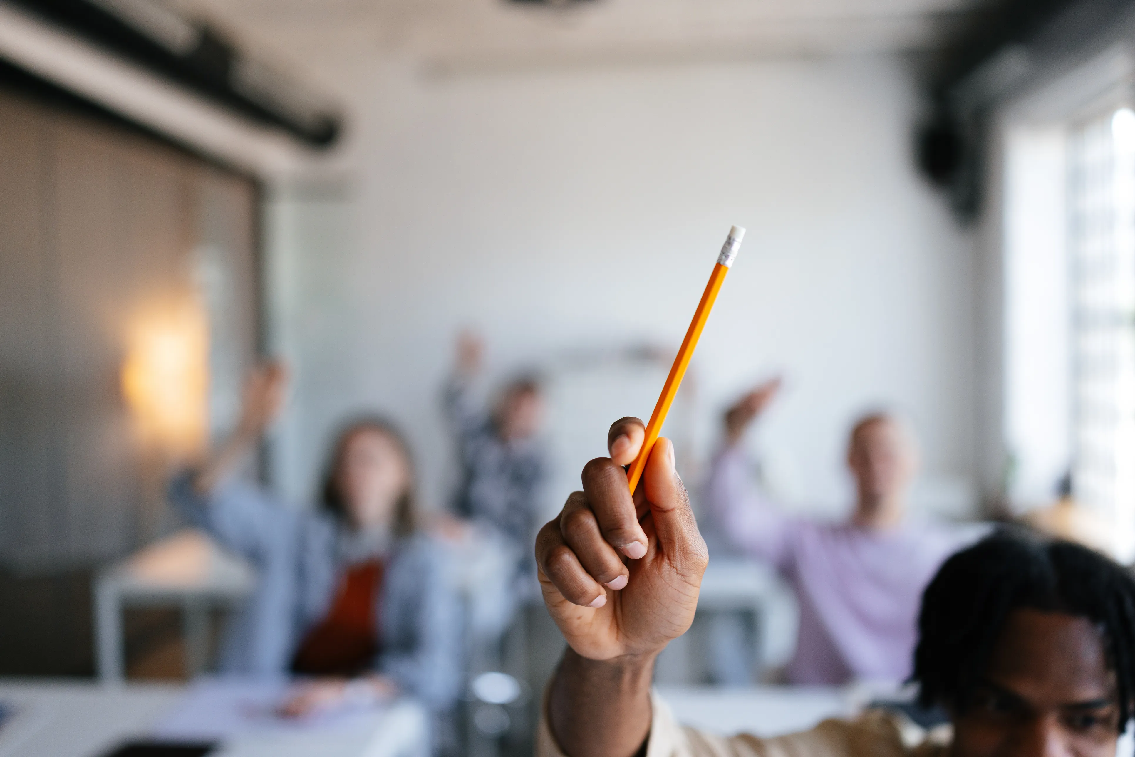 kid holding up pencil in class to speak