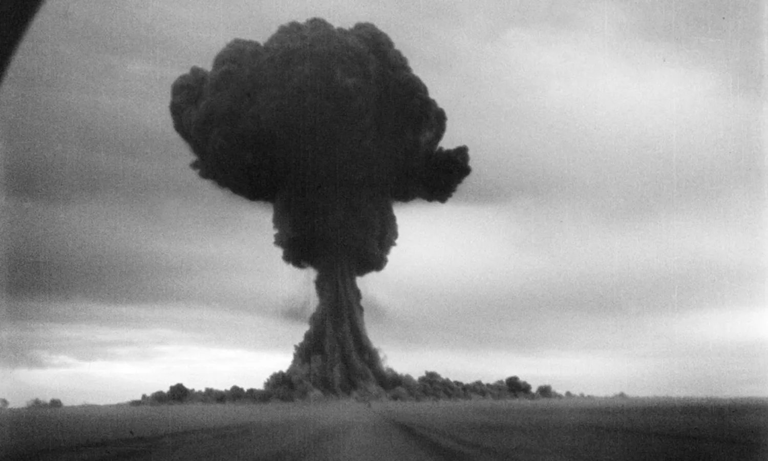 A black and white photograph of a large, black mushroom cloud.