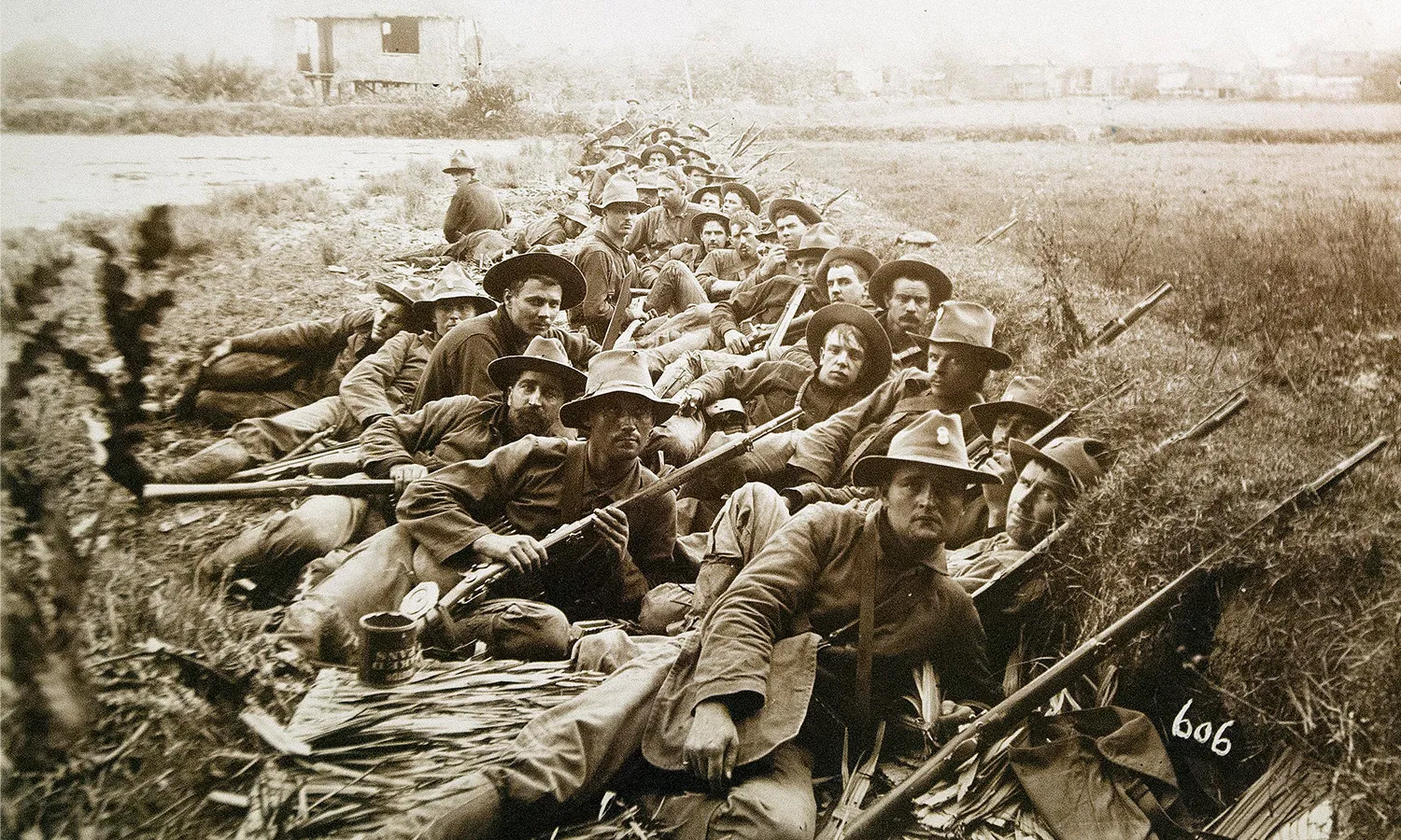 Black and white photograph of American soldiers lying in trenches holding guns during the Philippine-American War.
