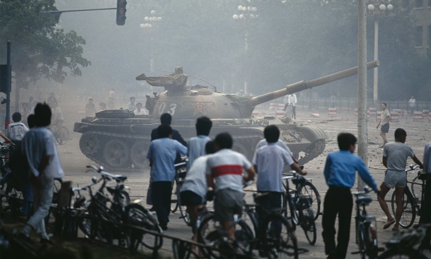 Chinese tank in Tiananmen Square with many people with bikes watching the military bloodily suppress a demonstration.